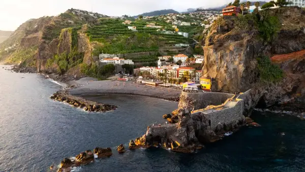 Ponta do Sol, Madeira: malerische Küstenstadt mit terrassierten Bananenplantagen, einem Kiesstrand und einer beeindruckenden Felsformation mit einem steinernen Aussichtsweg.