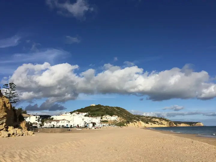Sonne, Sand und weiße Häuser: Ein malerischer Blick auf Salema, Portugal, mit dem Atlantik und dramatischen Wolken.